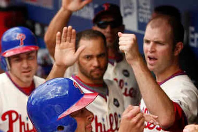 Shane Victorino is congratulated in the dugout after he and Chase Utley (left) scored on Ryan Howard's double in the four-run fifth inning. The Phillies scored six more in the seventh inning.