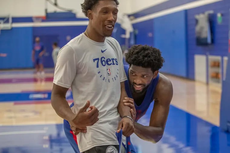 Joel Embiid, right, hides behind teammate Josh Richardson to avoid getting his photograph taken by the Sixers photographer after practice Sunday.