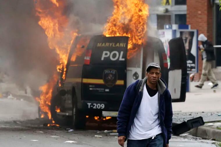 A man walks past a burning police van during unrest after the funeral of Freddie Gray in Baltimore. Gray died from spinal injuries about a week after he was arrested and transported in a Baltimore Police Department van.