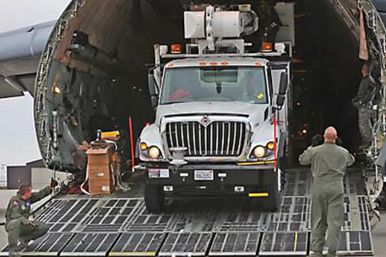 Load masters directs a driver out of the huge cargo plane. The first two Air National Guard cargo jets of 17 arrived at Stewart Air National Guard Base in Newburgh, N.Y., on Thursday, Nov. 1, 2012. The C-5a Galaxies and C-17's were ferrying some of the total 632 tons of relief equipment and supplies from the west coast to the east coast. Originating in Southern California at March Air Force Base the first two cargo planes brought in five bucket trucks and 3 pickup trucks along with personnel from the utility, Southern California Edison. (AP Photo/Times Herald-Record, Jeff Goulding)