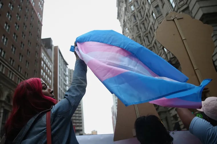 A woman raises up a transgender pride flag during a 2018 march in Philadelphia. The city this month enacted new regulations aimed at protecting transgender youth.