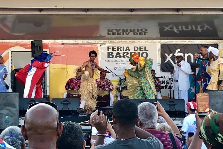 Music group Hermanos Ayala performs at the 35th Feria del Barrio, at Fifth Street and Lehigh Avenue, joined by two vejigantes on Sunday.