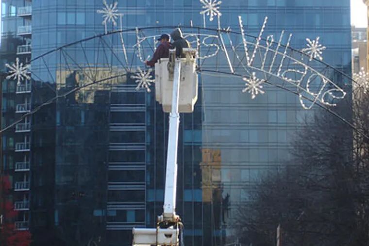 Crews remove the word "Christmas" from the sign at Dilworth Plaza. (VANCE LEHMKUHL / Staff)