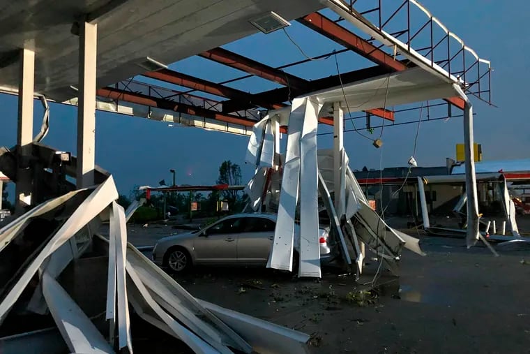 A car is trapped under the fallen metal roof of the Break Time gas station and convenience store in tornado-hit Jefferson City, Mo., on Thursday.