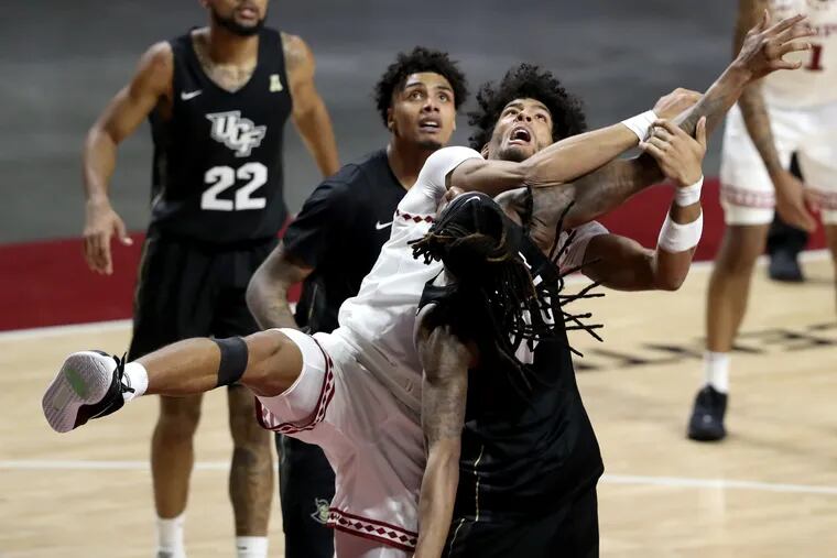Jake Forrester, center in white uniform, of Temple  gets tangeled up with C.J. Walker  of Central Florida as they battled for a rebound during the 2nd half at the Liacouras Center on Jan. 14,, 2021.