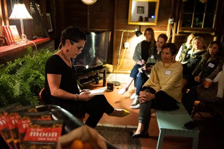 Lisa Kohn, a leadership consultant and coach from Wayne, reads an excerpt from her book, to the moon and back, at a gathering at home of neighbor Elaine Marnell (right, front).