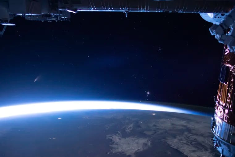 In this image released by NASA, Comet Neowise, left, is seen in the eastern horizon above Earth in this image taken from the International Space Station last week.
