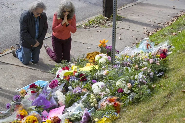 A couple kneels before a memorial at Murray and Wilkins Ave. on Oct. 28, 2018. The memorial was for the 11 people that were killed at the shooting at the Tree of Life Synagogue.