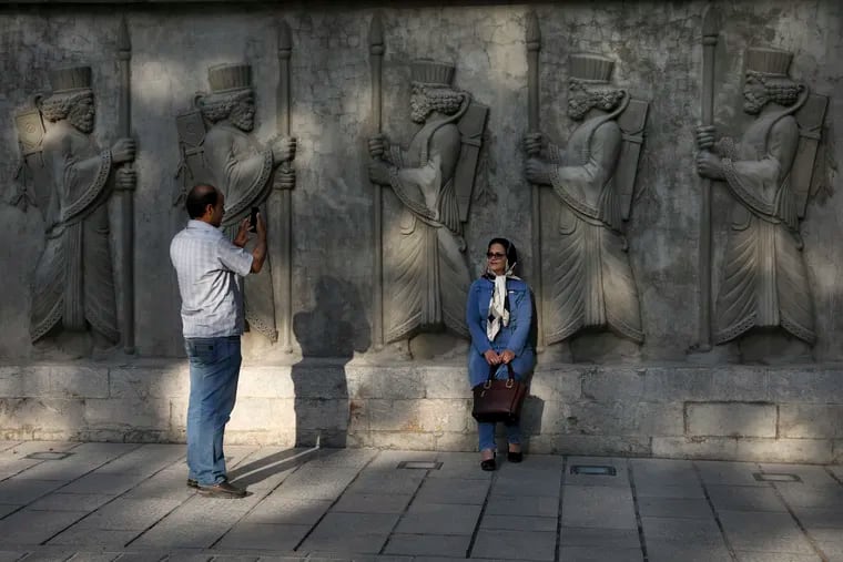 In this Saturday, May 18, 2019 photo, a couple takes photos with bas reliefs of ancient Persian soldiers in an old neighborhood in downtown Tehran, Iran. The Associated Press spoke to a variety of people on Tehran’s streets recently, ranging from young and old, women wearing the all-encompassing black chador to those merely loosely covering their hair. (AP Photo/Vahid Salemi)