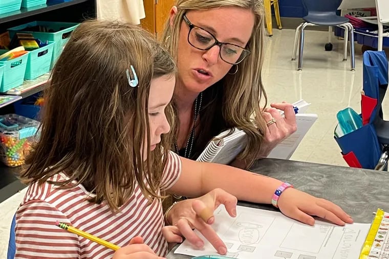 Hailey Lang at Burrus Elementary in Hendersonville, Tenn., helps a kindergarten student count up her circles and then translate those into numbers for an addition problem.