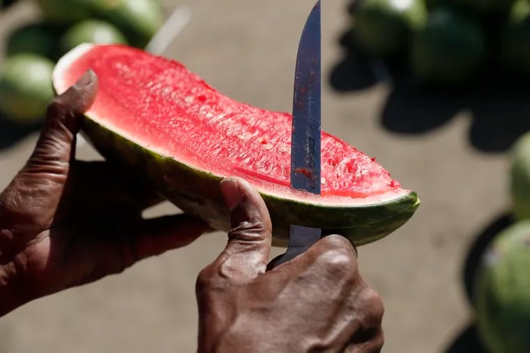 Joshua Carter carves a watermelon for display purposes at the Carter family business, selling watermelon at the corner of 84th and Lindbergh in SW Philly on Sept. 5.