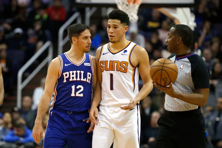Philadelphia 76ers guard T.J. McConnell (12) and Phoenix Suns guard Devin Booker (1) talk in the first half during an NBA basketball game, Wednesday, Jan. 2, 2019, in Phoenix. (AP Photo/Rick Scuteri)