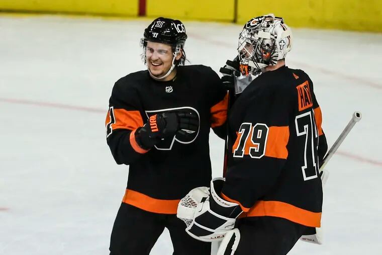 Flyers right winger Travis Konecny celebrates with goalie Carter Hart after beating the Pittsburgh Penguins, 5-2, at the Wells Fargo Center on Friday. Konecny had a hat trick and Hart was outstanding in the nets.