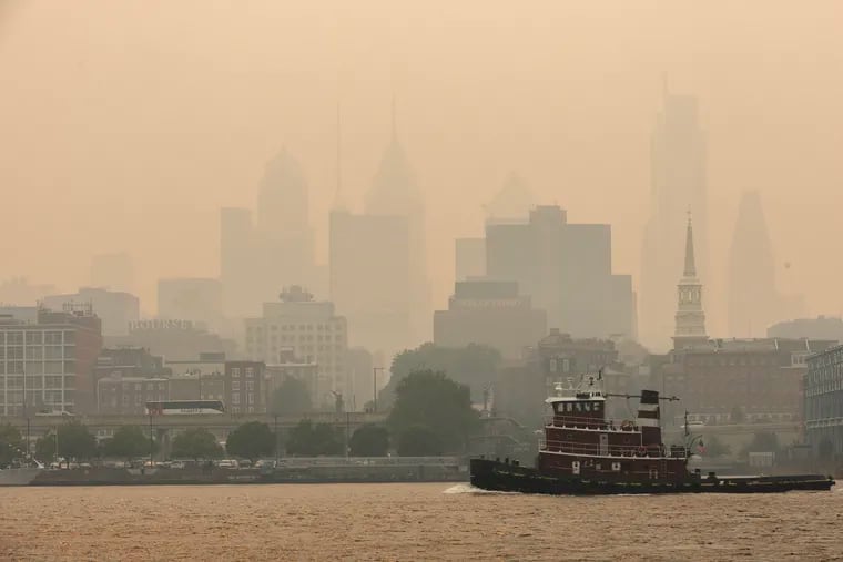 A tugboat goes down the Delaware River against the haze of the Philadelphia skyline on June 7, 2023. Smoke from Canadian wildfires shrouded much of the Northeast like a fog.