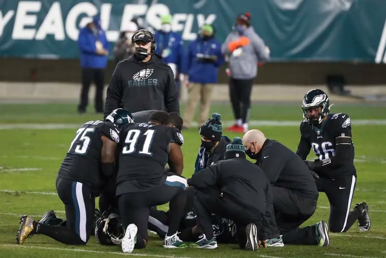 Players, Eagles coach Doug Pederson, and medical personnel huddle around Rodney McLeod, who suffered a torn ACL Sunday.