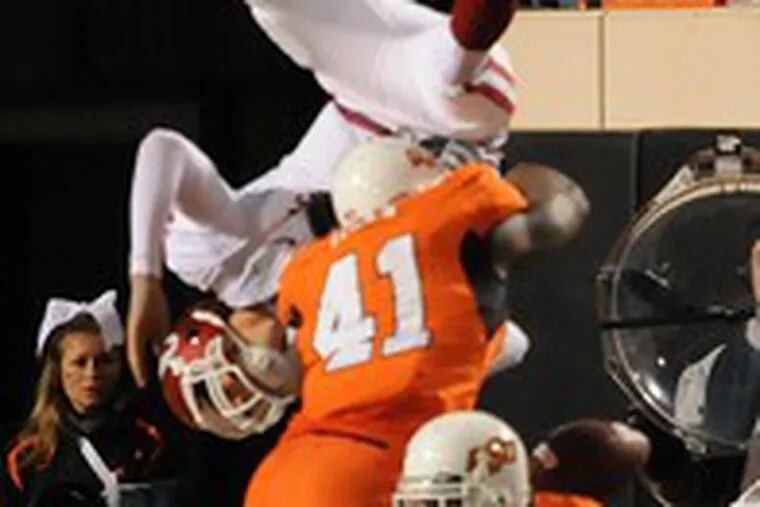 Oklahoma&#0039;s Sam Bradford (top) was turned upside-down by Oklahoma State&#0039;s Orie Lemon (41) and Ricky Price last month.