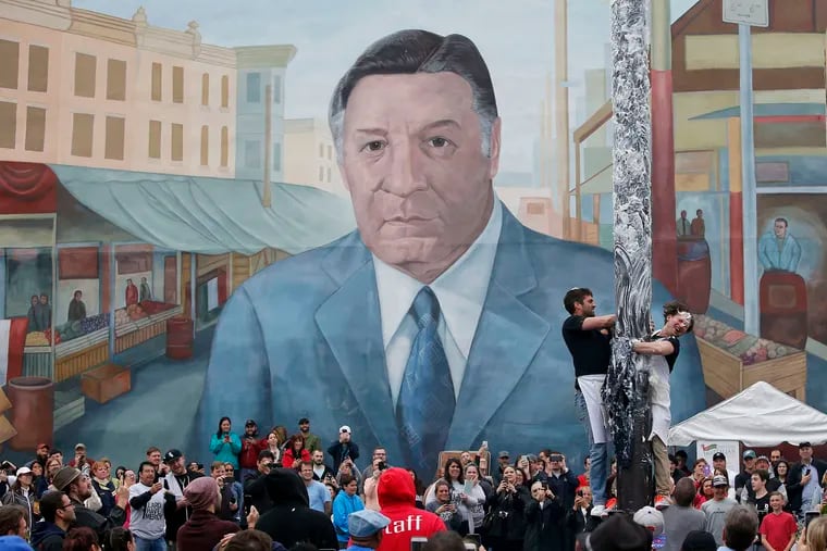 May 21, 2016: Participants try to climb the greased pole with the mural of former Philadelphia Mayor Frank Rizzo looking on at the South 9th Street Italian Market Festival.