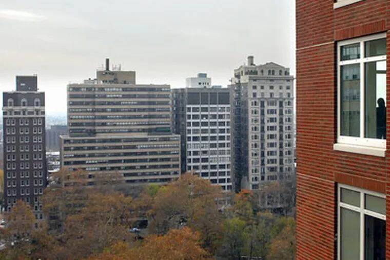 A guest (in window at far right) at yesterday's opening takes in the view at 10 Rittenhouse Square. (Tom Gralish / Staff)