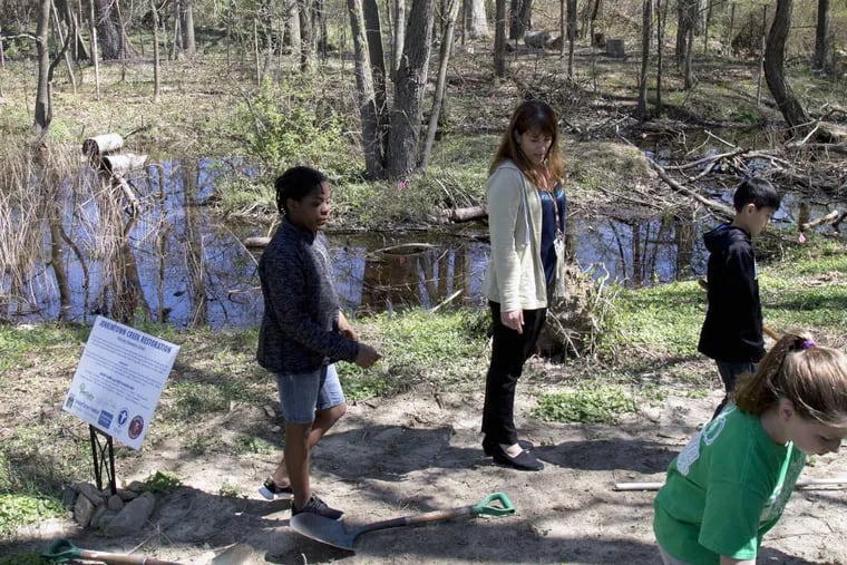 Teacher Jennifer Tanay (center) and  McKinley Elementary 5th graders from her Roots and Shoots environmental club (from left: Dylan Britt, Steven Thai and Iris Winegrad) explore a section of Jenkintown Creek on school grounds that they helped revitalize.