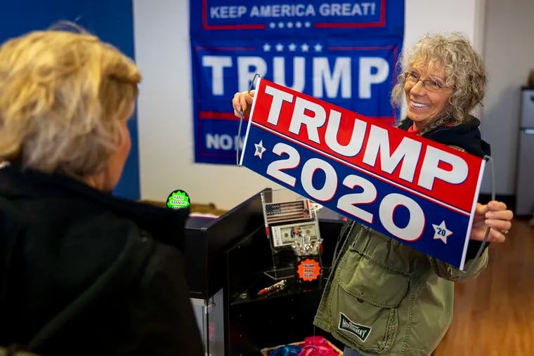 Theresa Gabriella-Frey, 71, of Croydon, Pa., shows her Trump 2020 banner she's buying to another customer at the new Trump Store in Bensalem, Pa., on Tuesday, Feb. 11, 2020.