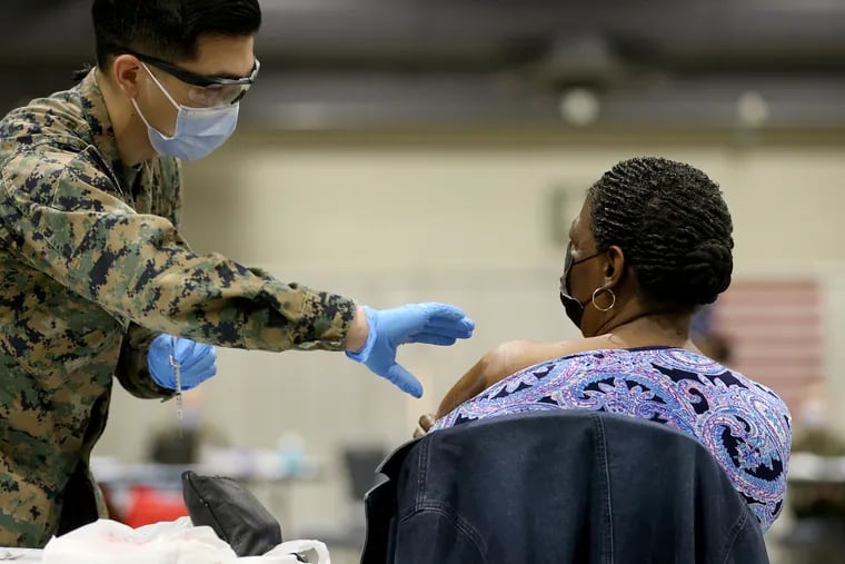 Joseph Delacruz (left) prepares to vaccinate Ava Rollins (right) at the FEMA-run vaccination site at the Pennsylvania Convention Center. Four thousand Pfizer vaccine doses were removed from cold storage earlier this week, and the city has administered about 1,000 so far. But with demand for vaccinations plateauing, the city faces the prospect of thousands of vaccine doses expiring before they can be used.