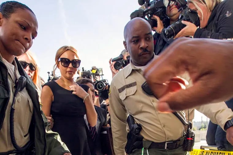 Lindsay Lohan is escorted by Los Angeles County Sheriffs as she arrives in court for a pretrial hearing in a case filed over the actress' June car crash in Los Angeles Wednesday, Jan. 30, 2013. Lohan faces three misdemeanor charges, and a return to jail, if convicted in the case or if a judge finds she violated her probation.(AP Photo/Damian Dovarganes)