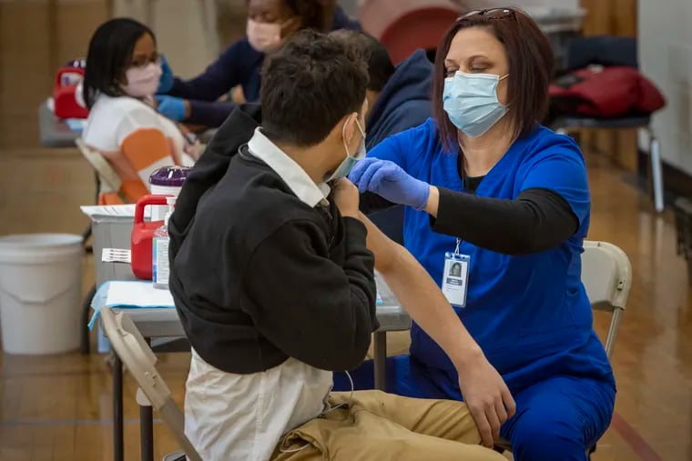 Pictured at right is registered nurse, Sherry Holbrook giving a student a COVID-19 vaccine in Northeast High School gymnasium. Dr. Ala Stanford (not shown) visited Northeast High School at 1601 Cottman Ave, Philadelphia on a day students can get vaccinated against COVID-19, Wednesday, February 2, 2022.