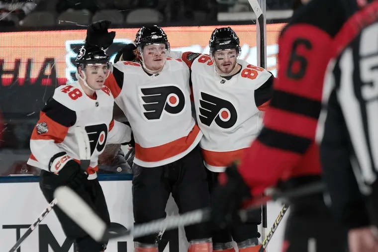 The Flyers' Morgan Frost (left) and Joel Farabee (right) celebrate Owen Tippett’s second goal against the Devils at MetLife Stadium on Saturday.