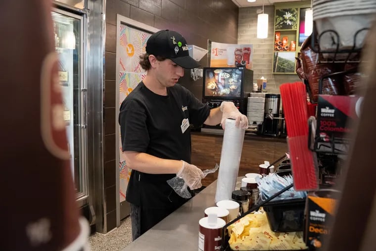 Michael Franolich, 25, a Wawa employee works on stocking the coffee cup lids at the coffee station in Wawa in Collingswood, New Jersey on July 10, 2019. Experts recommend that small businesses use local companies like Wawa for their coffee.