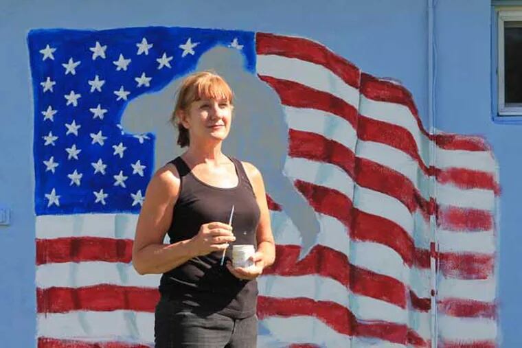 Local artist Mary Barnett is painting a patriotic mural on the Maple Shade VFW post on June 19, 2014. She hopes to have the mural done in a few days.  This flag will have a wounded warrior painted in the middle of the flag.  ( CHARLES FOX / Staff Photographer )