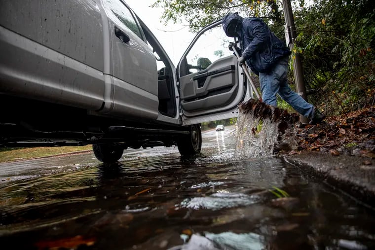 A city worker unplugs the clogged drain of leaves and trash from the rainfall from remnants of hurricane Zeta on Thursday, Oct. 30, 2020.