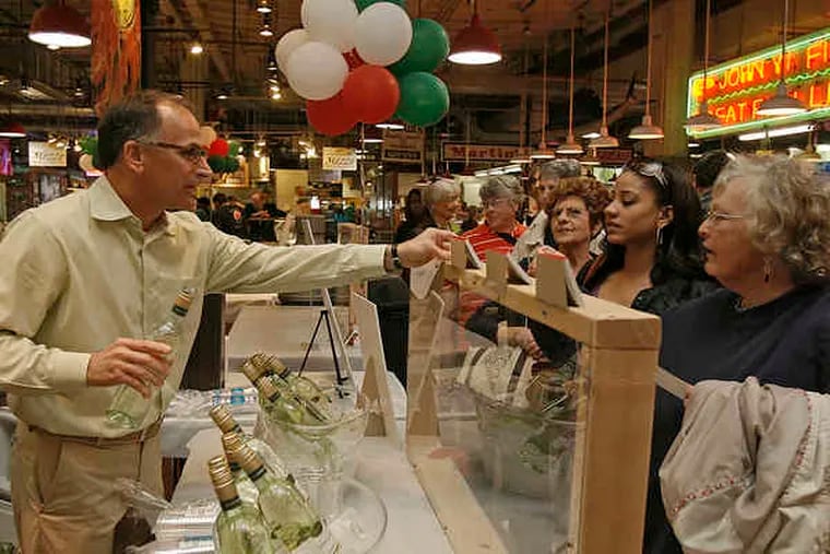 Bart Pio of Pio Imports hands out samples of wine to customers at Reading Terminal Market, including (from right) Karen Wildof Harrisburg, Andrea Brown of Northeast Philadelphia, and Kathy Nuspl of Harrisburg.
