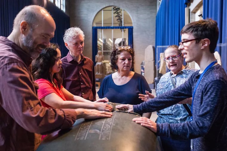 David Goldstein, Harriet Go, and Simon Bonenfant feel the hieroglyphics etched into a sarcophagus at Penn Museum of Archaeology and Anthropology.