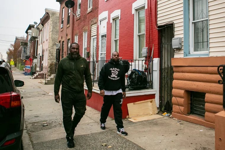 Robert Warne (right) and mentee Jermaine McElveen walk in their North Philadelphia neighborhood recently. Warner runs a program to help prevent gun violence by providing support to the community.