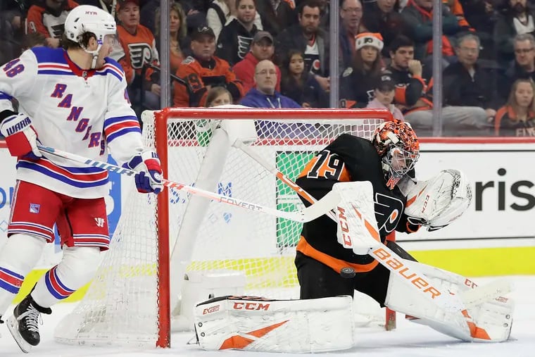 Flyers goaltender Carter Hart, shown stopping the Rangers' Brendan Lemieux on Monday, is now fifth in the NHL with a 2.27 goals-against average. Hart and his teammates will try to improve their road record during an upcoming six-game trip.