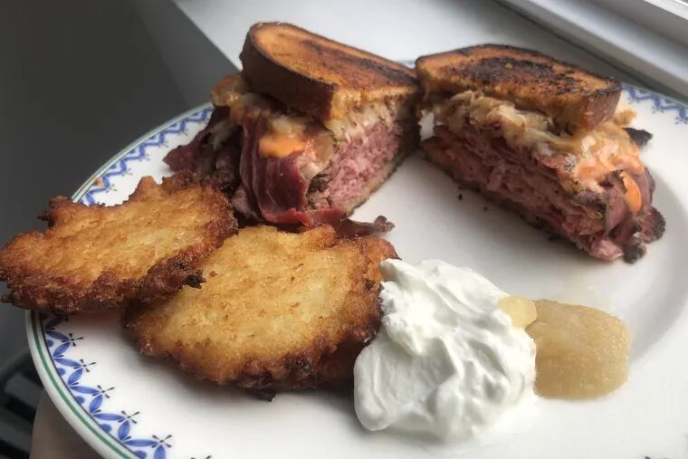 A corned beef and pastrami Reuben from Schlesinger's Deli, with a side of crispy potato pancakes.