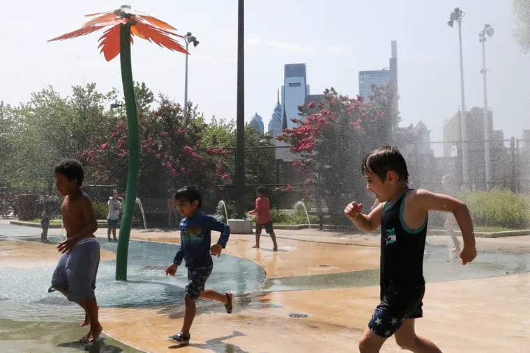 Kids cool off at the spray park inside Roberto Clemente Park in Fairmount. It's been one steamy summer, despite lack of records.