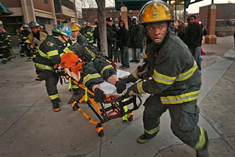 An injured firefighter is rushed away Wednesday morning from a high-rise fire at the Norman Blumberg apartments at 24th and Jefferson streets in North Philadelphia. (Alejandro A. Alvarez/Staff)