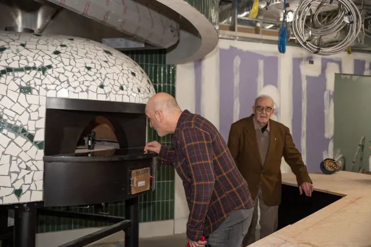 Chef Marc Vetri pokes inside the new oven at Pizzeria Salvy at the Comcast Technology Center while his father, Sal, supervises.