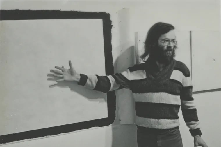Tony Conrad at a 1977 exhibition, in front of his painting “Yellow Movie 2/2/73”