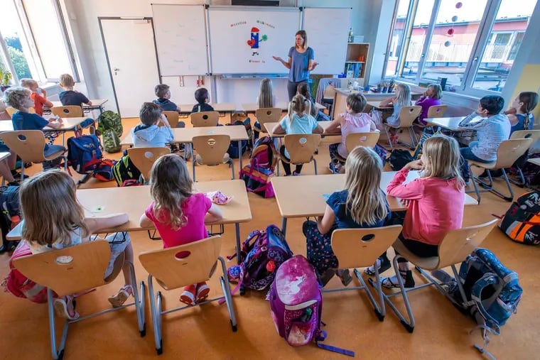 Teacher Francie Keller welcomes the pupils of class 3c in her classroom in the Lankow primary school to the first school day after the summer holidays in Schwerin, Germany, Monday, Aug. 3, 2020.