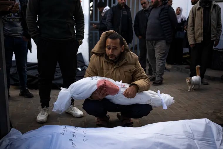 A man holds the body of his daughter at a hospital morgue in Rafah on Feb. 21. She was killed in the Israeli bombardment of the Gaza Strip.