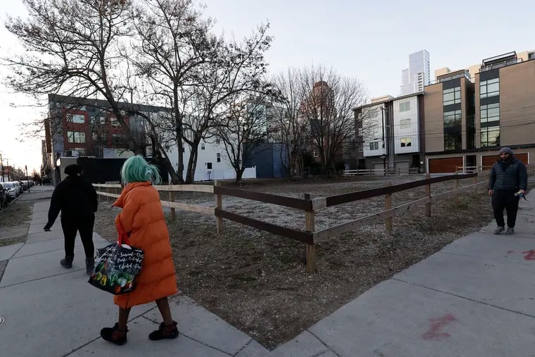 Pedestrians walk near the vacant lot at the northwest corner of 13th and Bainbridge Streets on Monday. The city is trying to redevelop the site with a new experiment to increase affordable housing, by leasing the land to a developer who promises that a portion of new housing units will be affordable.