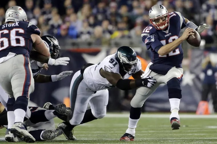 The Eagles’ Fletcher Cox (91), and the player he’s hanging onto, Tom Brady (12), a Patriots quarterback, could pay most of their Super Bowl earnings as taxes, New York sports accountant Robert Raiola calculates (AP Photo/Steven Senne, File)