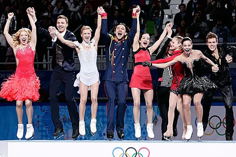 The Russian team jump onto the podium during the flower ceremony after placing first in the team figure skating competition. (Bernat Armangue/AP)