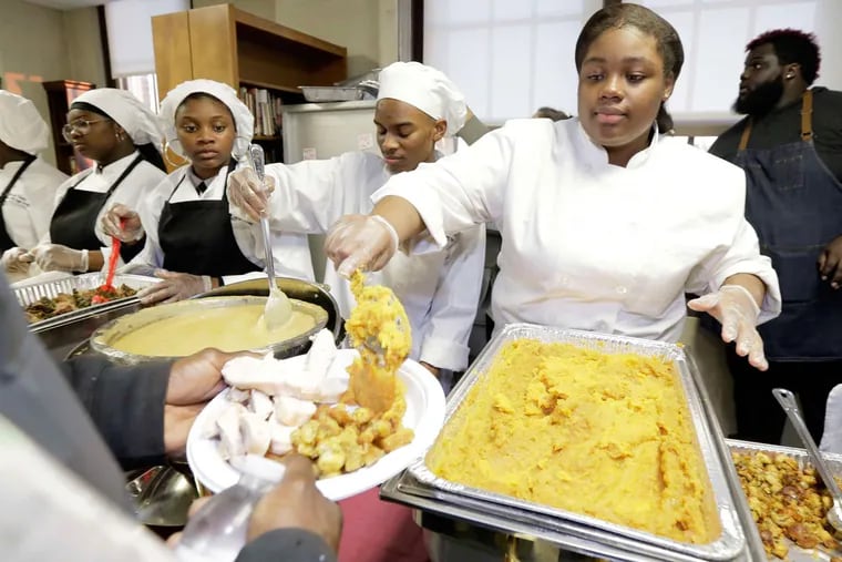 Kyarah Wallace serves up sweet potatoes during a holiday dinner at Dobbins Career and Technical Education High School in North Philadelphia.