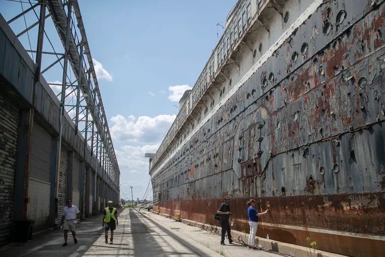 People including Susan Gibbs, whose grandfather, William Francis Gibbs, was the architect and engineer of the SS United States, walk along the ocean liner at Pier 82 in Philadelphia in July 2021.