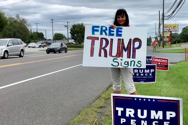 Beth Jones of Sinking Spring encourages drivers on Route 422 to stop for free yard signs for President Dona;d Trump&#39;s reelection campaign on Saturday, Sept. 12.