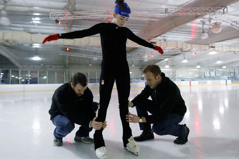 Students Garry Quinton (left) and Tyler Richardson apply reflective dots to figure skater Haley Beavers' bodysuit at the University of Delaware. Cameras in the ceiling will record her jumps.