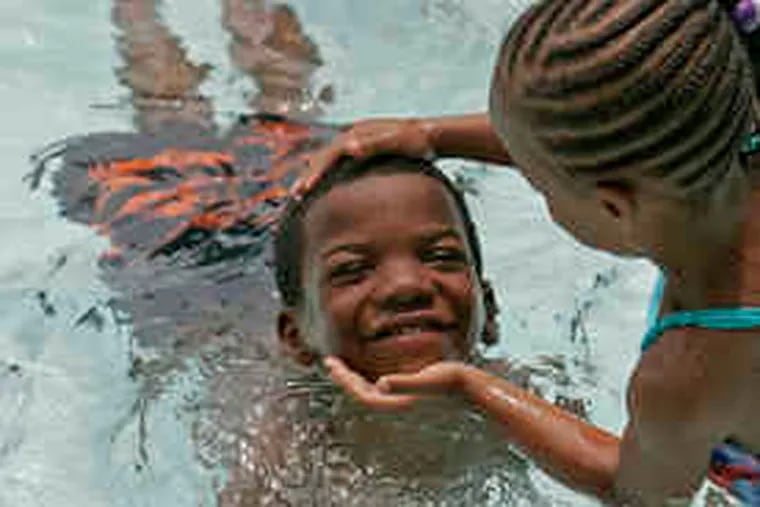 Rasheed Rose, 6, gets a little help from Rugayyah Colburn, 5, while swimming at the Hawthorne Recreation Center.
